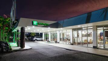 A Holiday Inn hotel with a modern design, featuring a spacious entrance, outdoor seating area, and a well-lit facade.