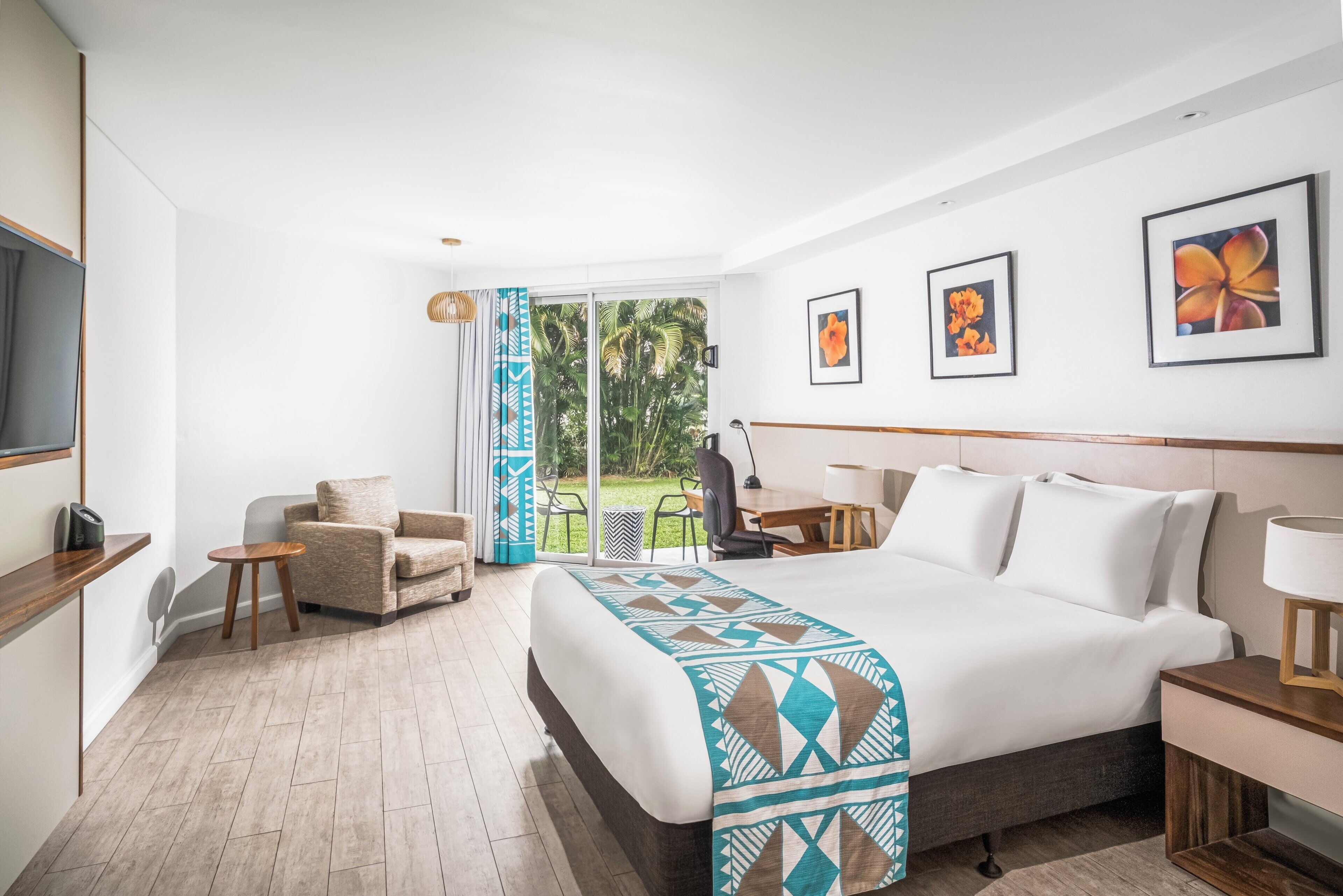 A hotel room with a large bed, a desk, a chair, and a television.