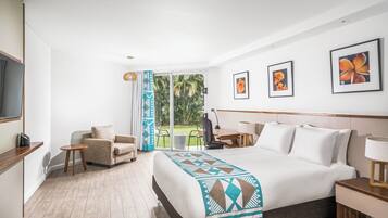A hotel room with a large bed, a desk, a chair, and a television.