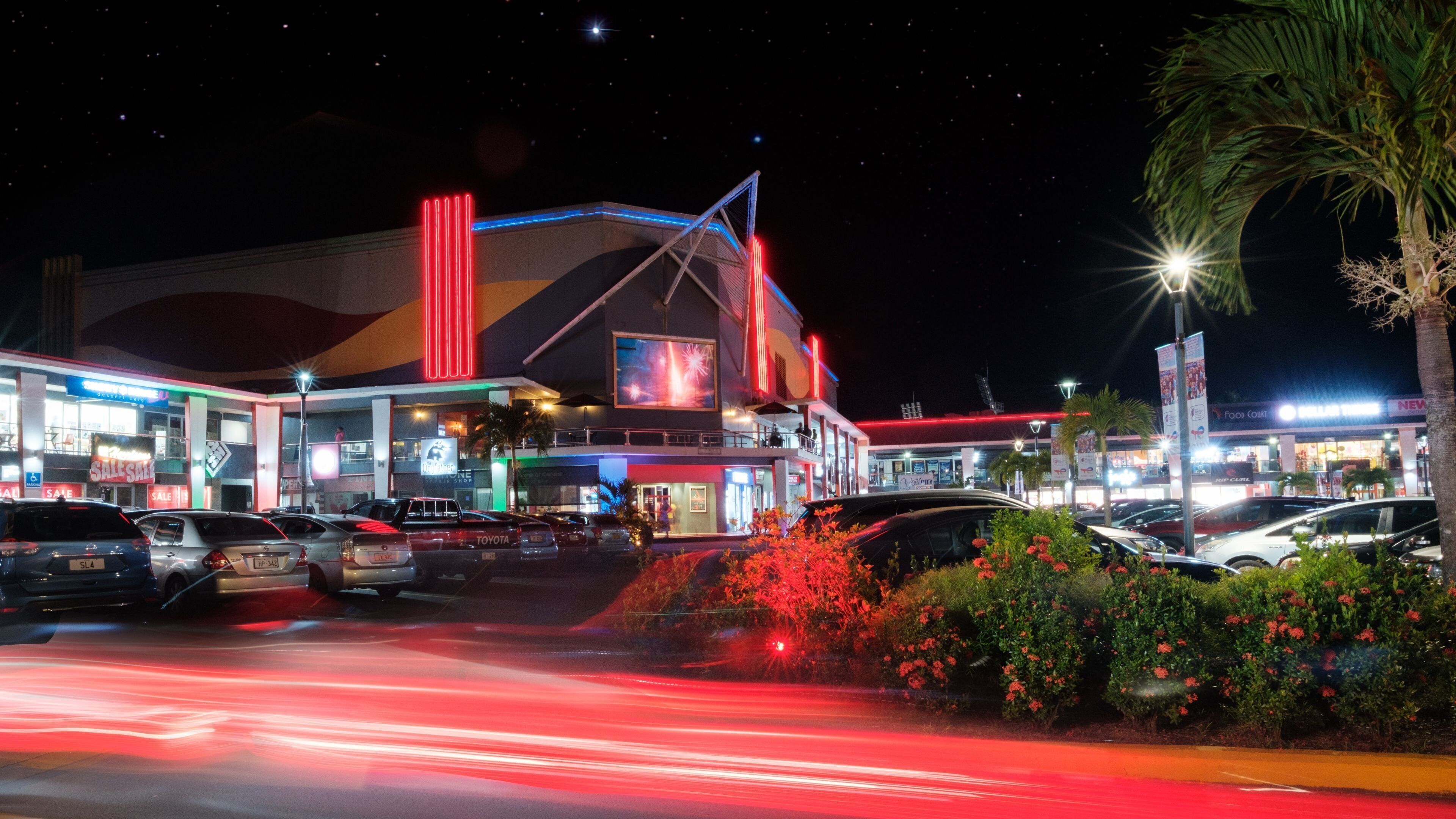 A brightly lit commercial building with multiple signs and a large illuminated display.