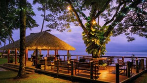 A wooden deck with outdoor seating, a thatched-roof structure, and a view of the water. - Holiday Inn Suva by IHG (Suva)
