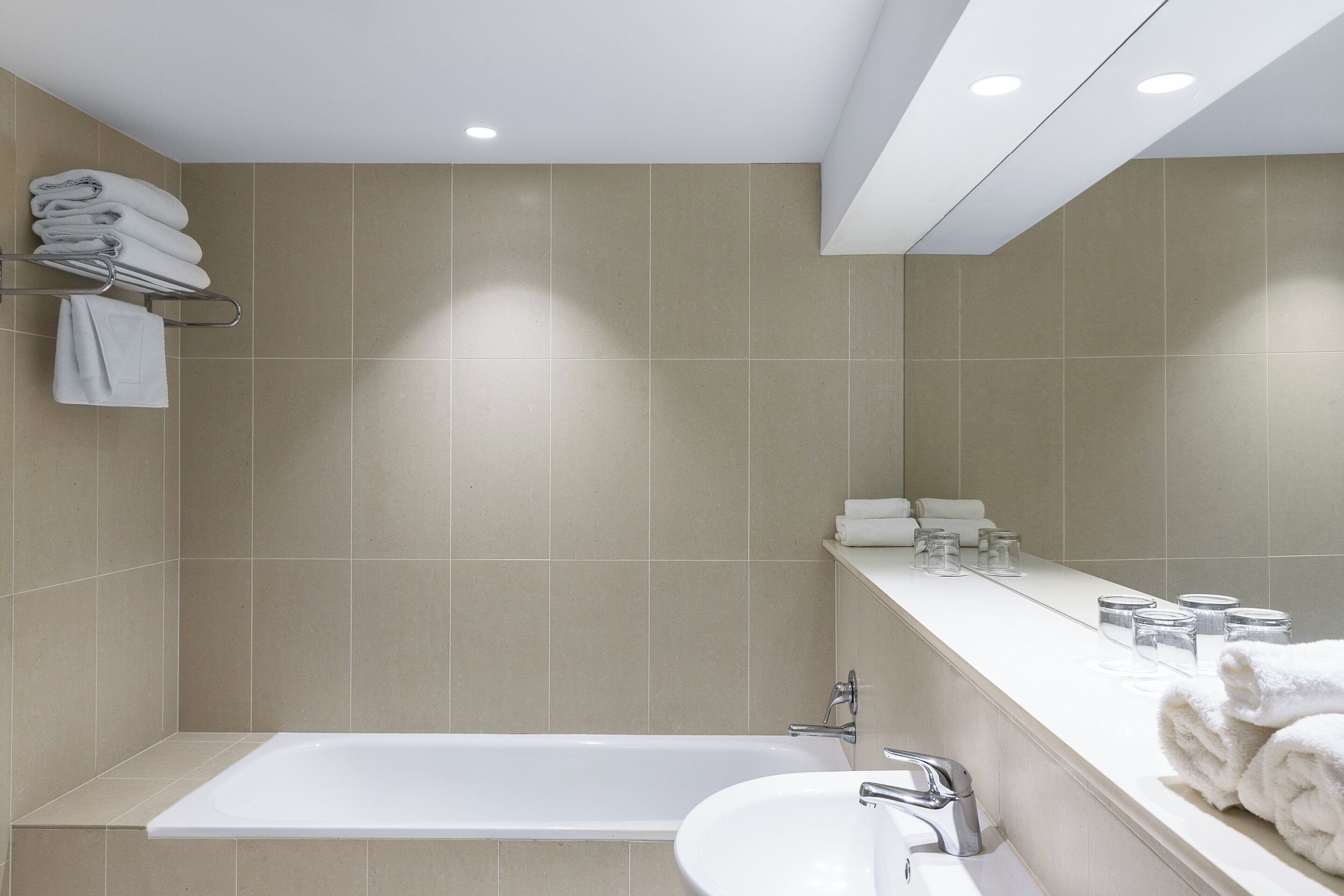 A modern bathroom with a bathtub, a sink, and a towel rack.