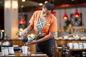 Um barista trabalhando, preparando uma bebida.