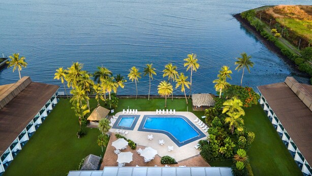 An aerial view of a resort with two swimming pools, palm trees, and a view of the ocean. - Holiday Inn Suva by IHG (Suva)
