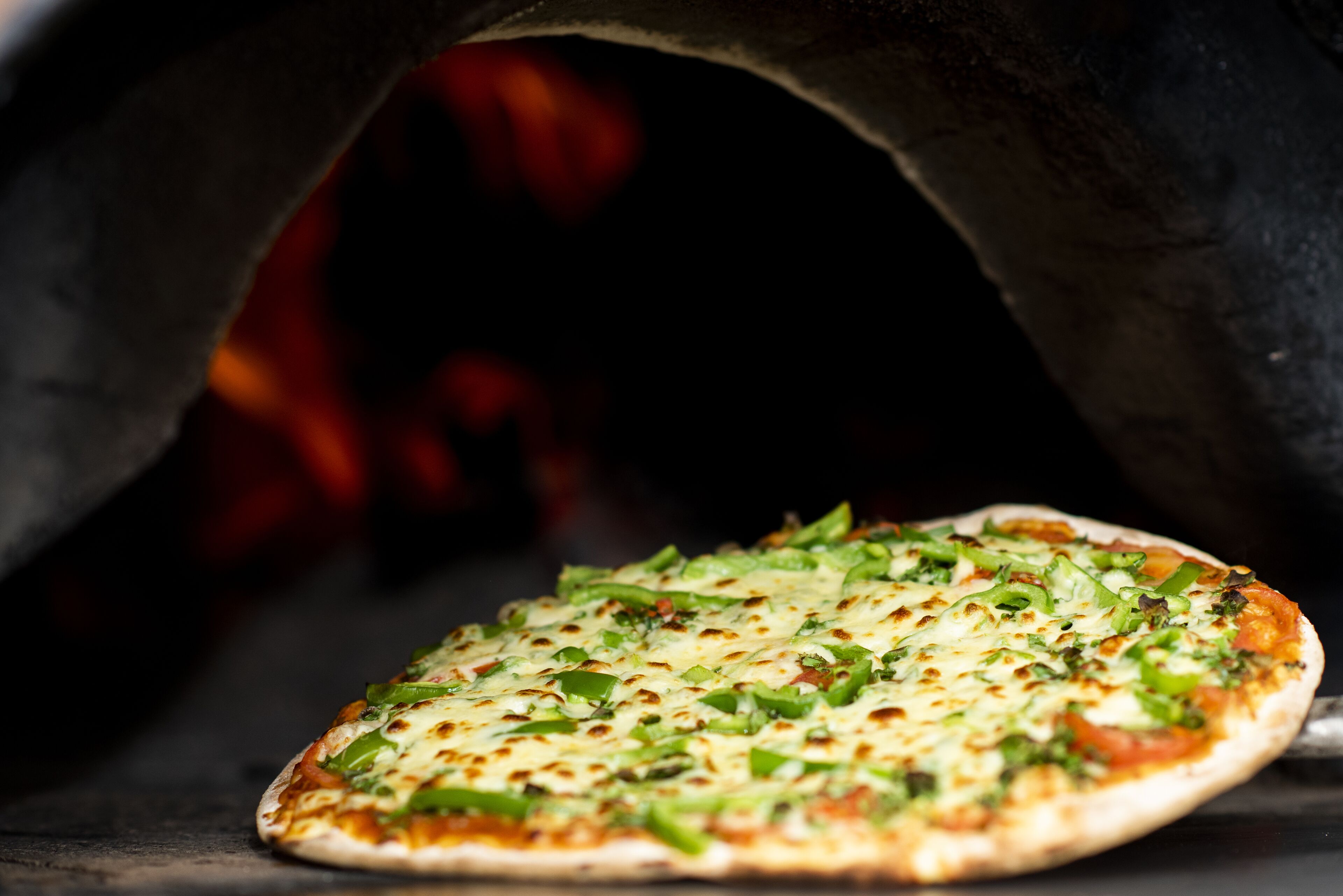A pizza inside a wood-fired oven.