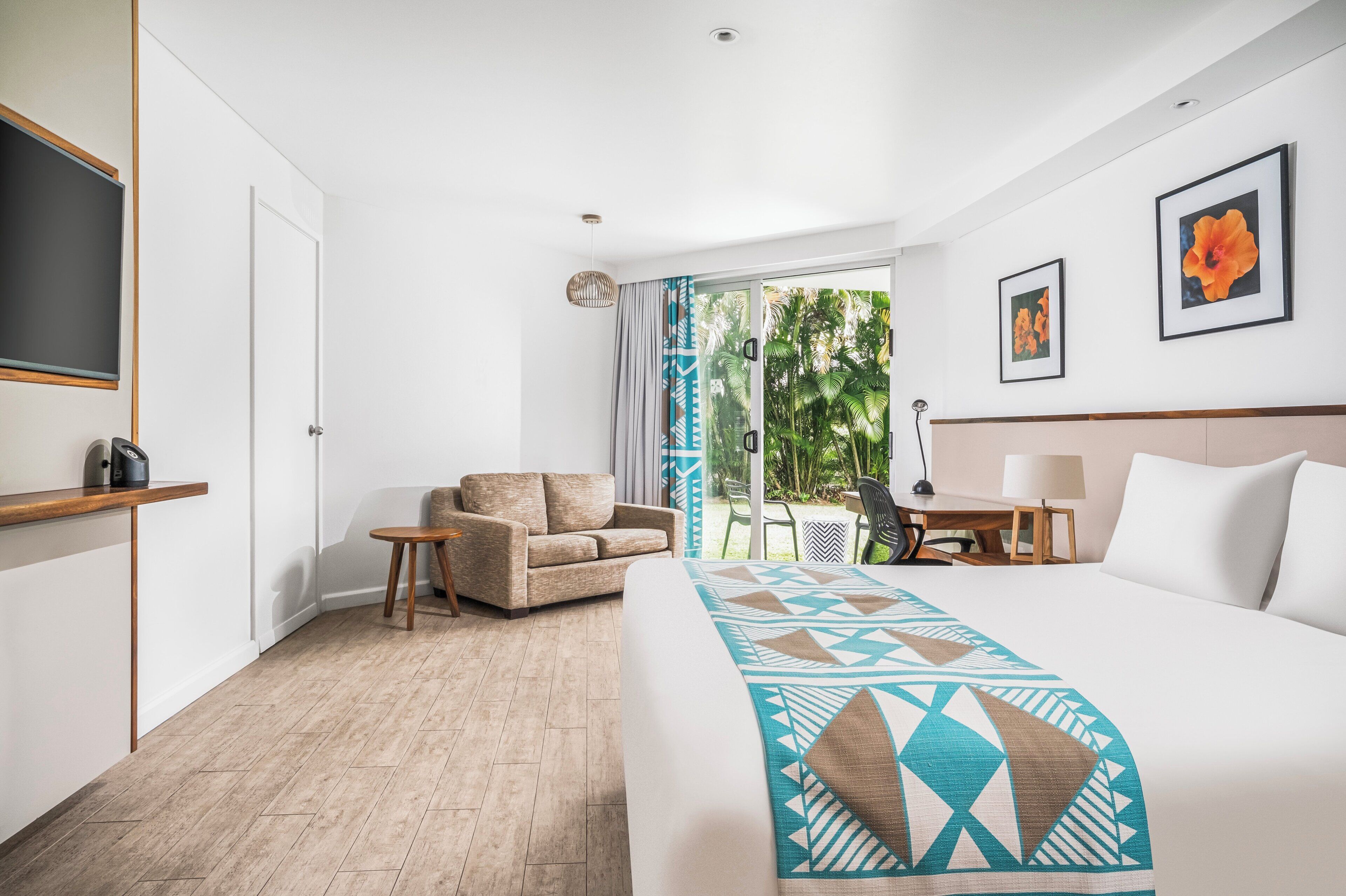 Habitación de hotel con cama, sofá, escritorio y vistas al exterior.