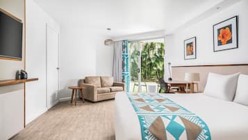 Habitación de hotel con cama, sofá, escritorio y vistas al exterior.