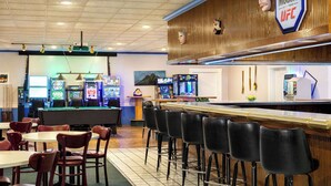 A bar area with arcade games, a counter, and bar stools.