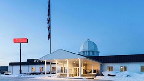 A hotel with a covered entrance, a dome structure, and a flagpole with an American flag.