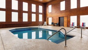 An indoor swimming pool with a hexagonal tile floor, wooden walls, and large windows.