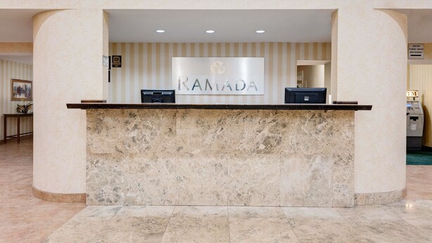 Una recepción con mostrador de mármol y un cartel que dice "RAMADA".