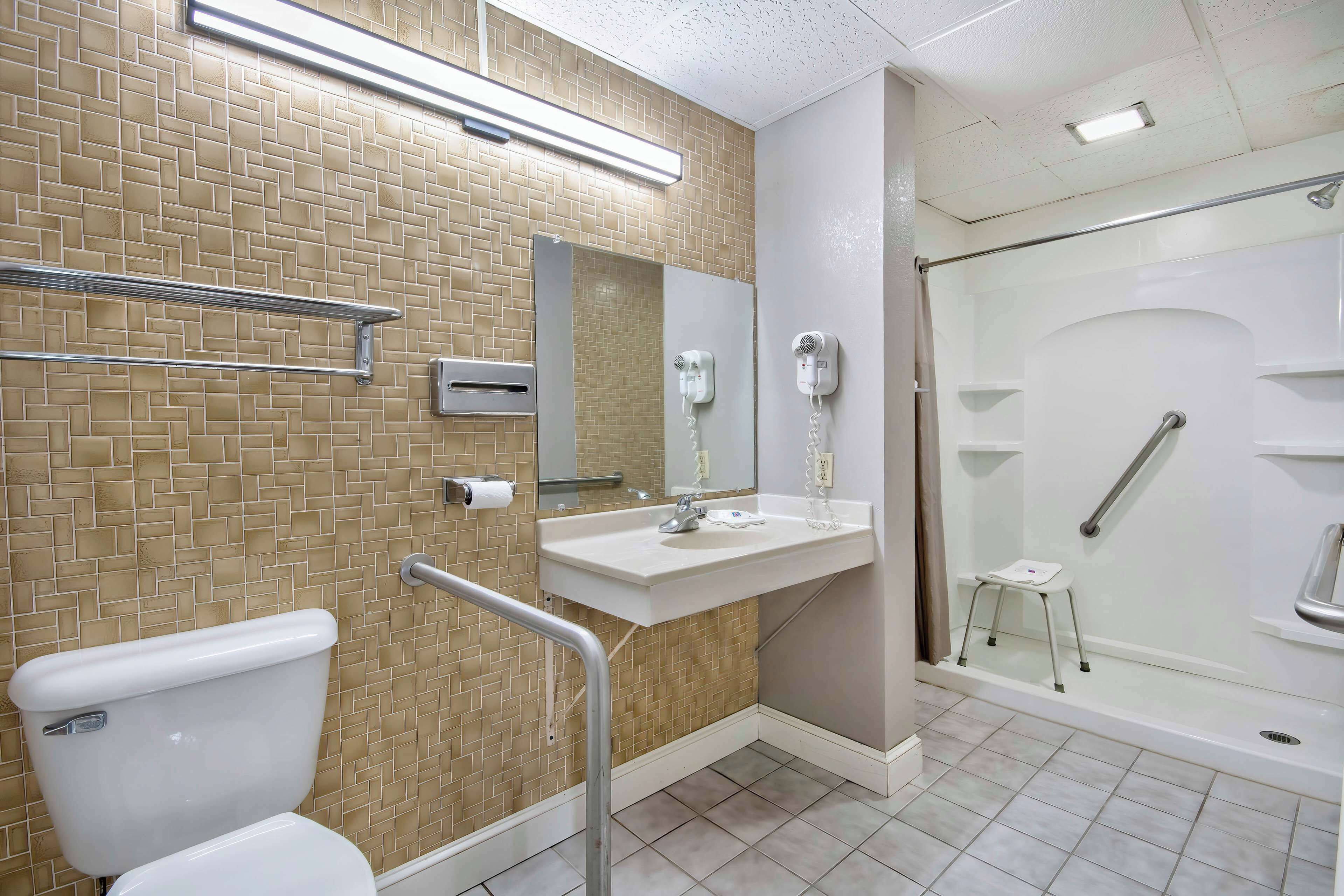 A bathroom with a toilet, sink, mirror, and shower.