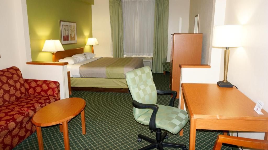 Ein Hotelzimmer mit einem Bett, einem Schreibtisch, einem Sessel, einer Couch und zwei Lampen.