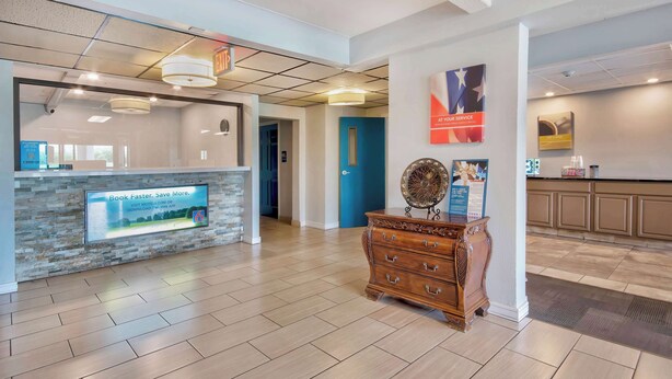 Un área de recepción con mostrador de piedra, cómoda de madera y puerta azul.