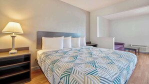 Una habitación de hotel con una cama, una mesita de noche, una lámpara, una silla y una pequeña mesa.