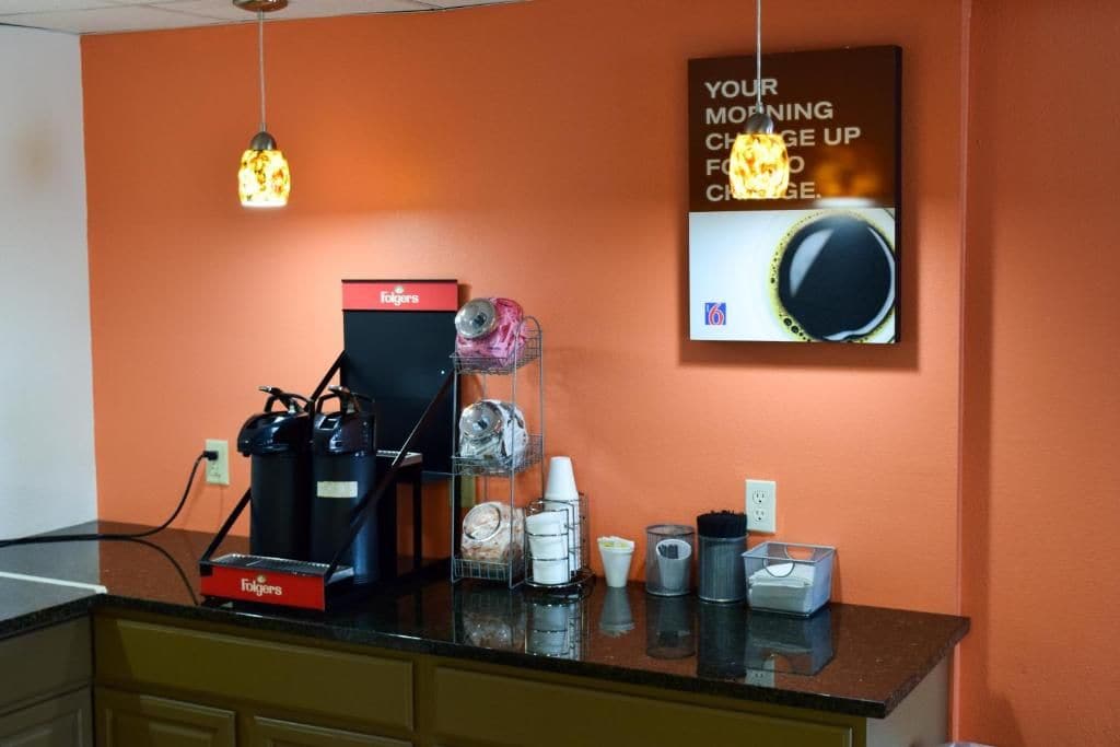 A coffee station with a Folgers coffee maker, a coffee grinder, and various coffee cups and containers.