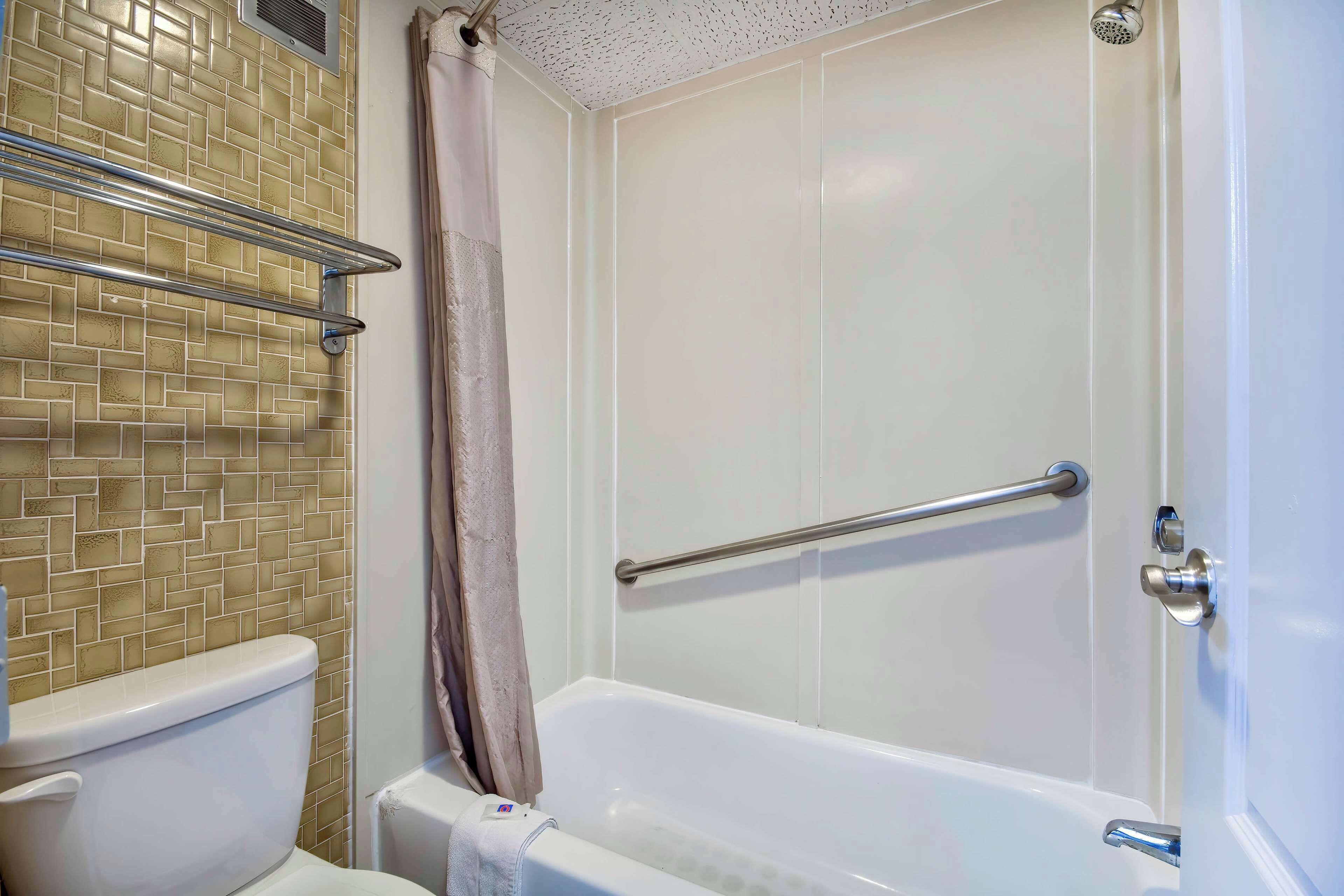 Un baño con pared de azulejos, bañera, inodoro y cortina de ducha.