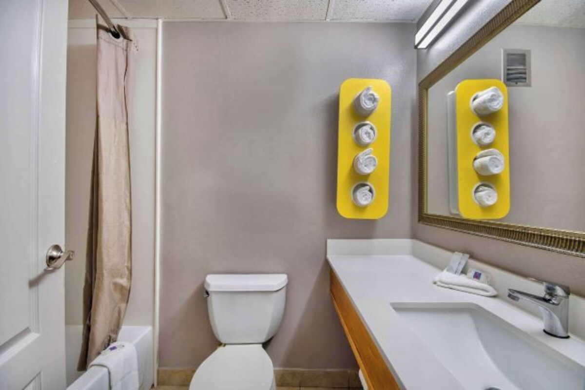 A bathroom with a toilet, a sink, and a mirror.