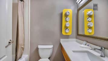 A bathroom with a toilet, a sink with a mirror, and a shower curtain.