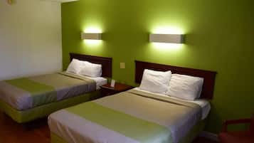 Habitación de hotel con dos camas individuales, cada una con cabecero de madera, mesita de noche y lámpara de pared.