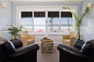 Una habitación con un amplio ventanal con vistas a la playa, dos sofás de cuero, una mesita de centro y una planta en maceta.