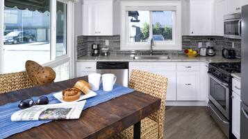 Une cuisine moderne avec des meubles blancs, une cuisinière en acier inoxydable et une fenêtre donnant sur la rue.