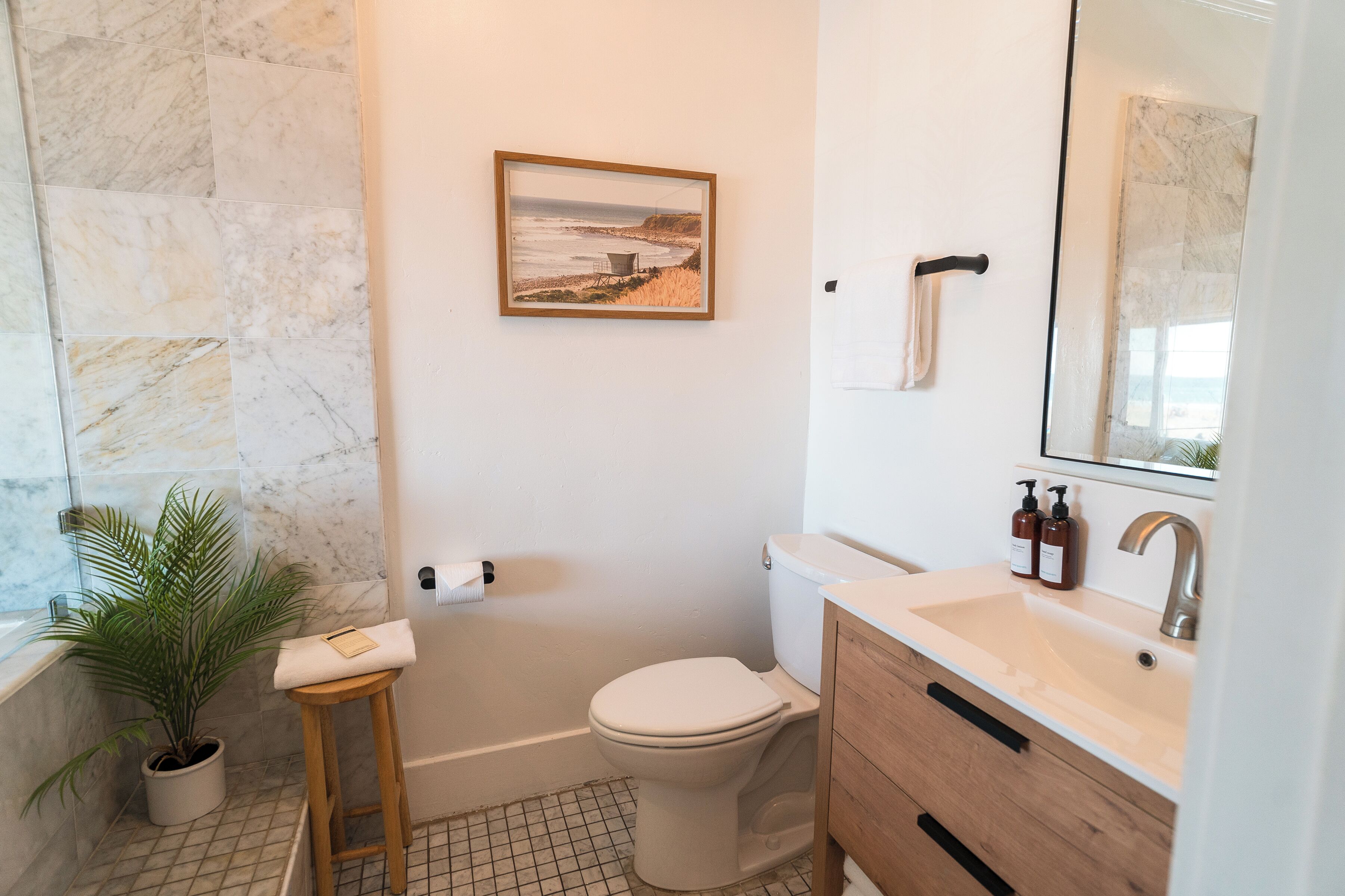 Un baño con bañera, inodoro, lavabo y un cuadro en la pared.