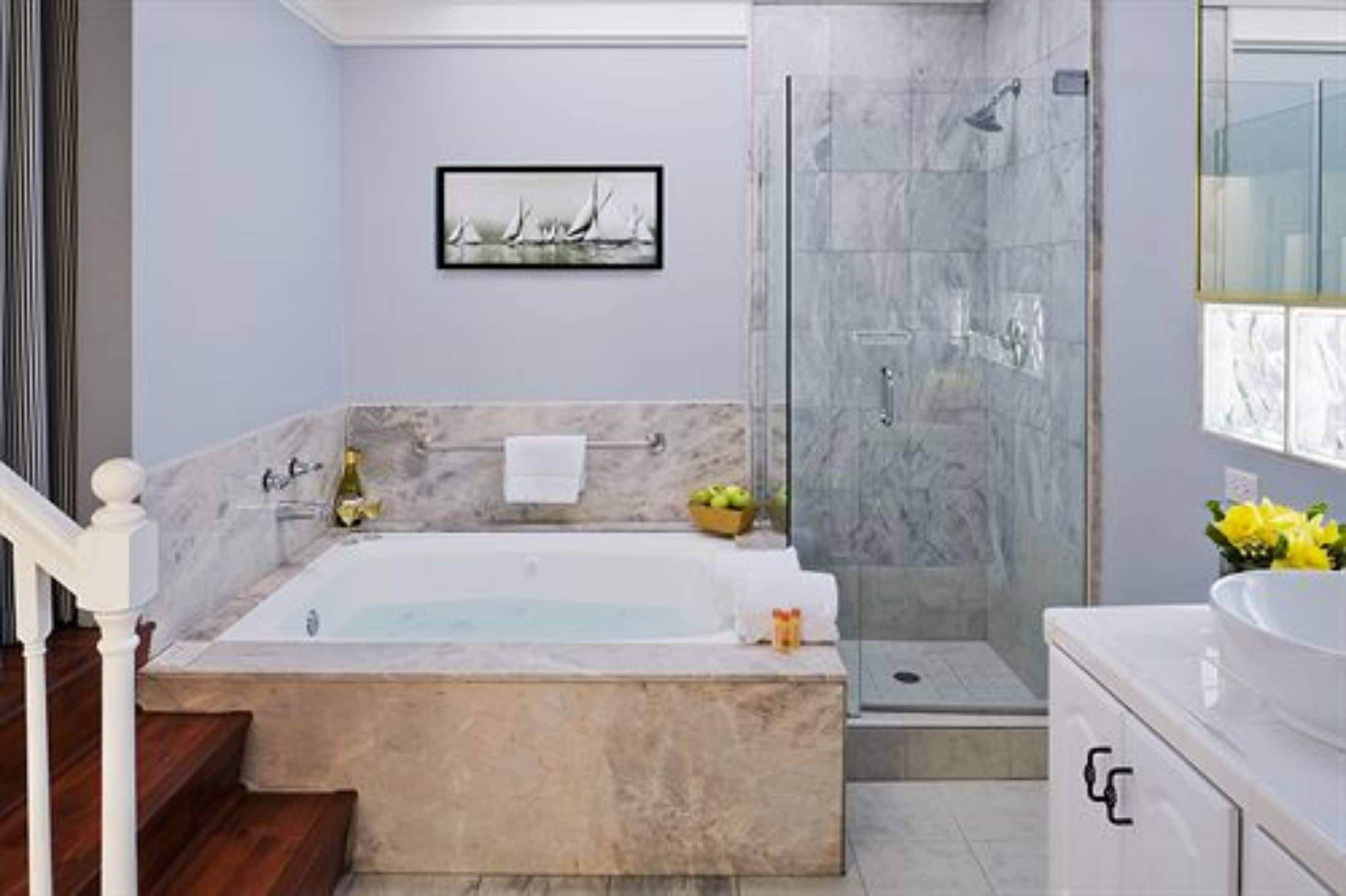 Un bagno moderno con una vasca freestanding, una doccia con pareti in vetro e un rivestimento in marmo.