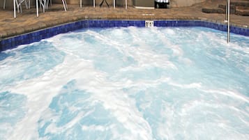 A swimming pool with a blue tiled edge, surrounded by a brick patio.