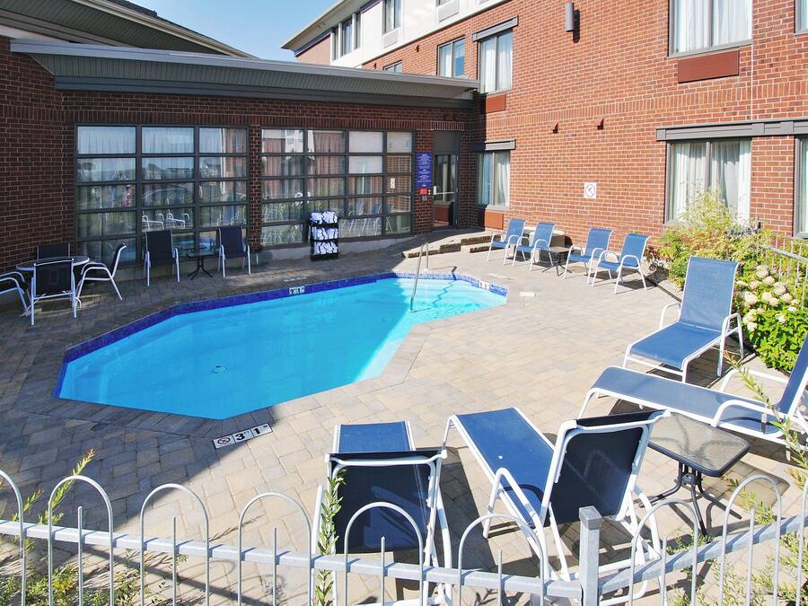 Une piscine avec des chaises longues et, en arrière-plan, un bâtiment en briques.