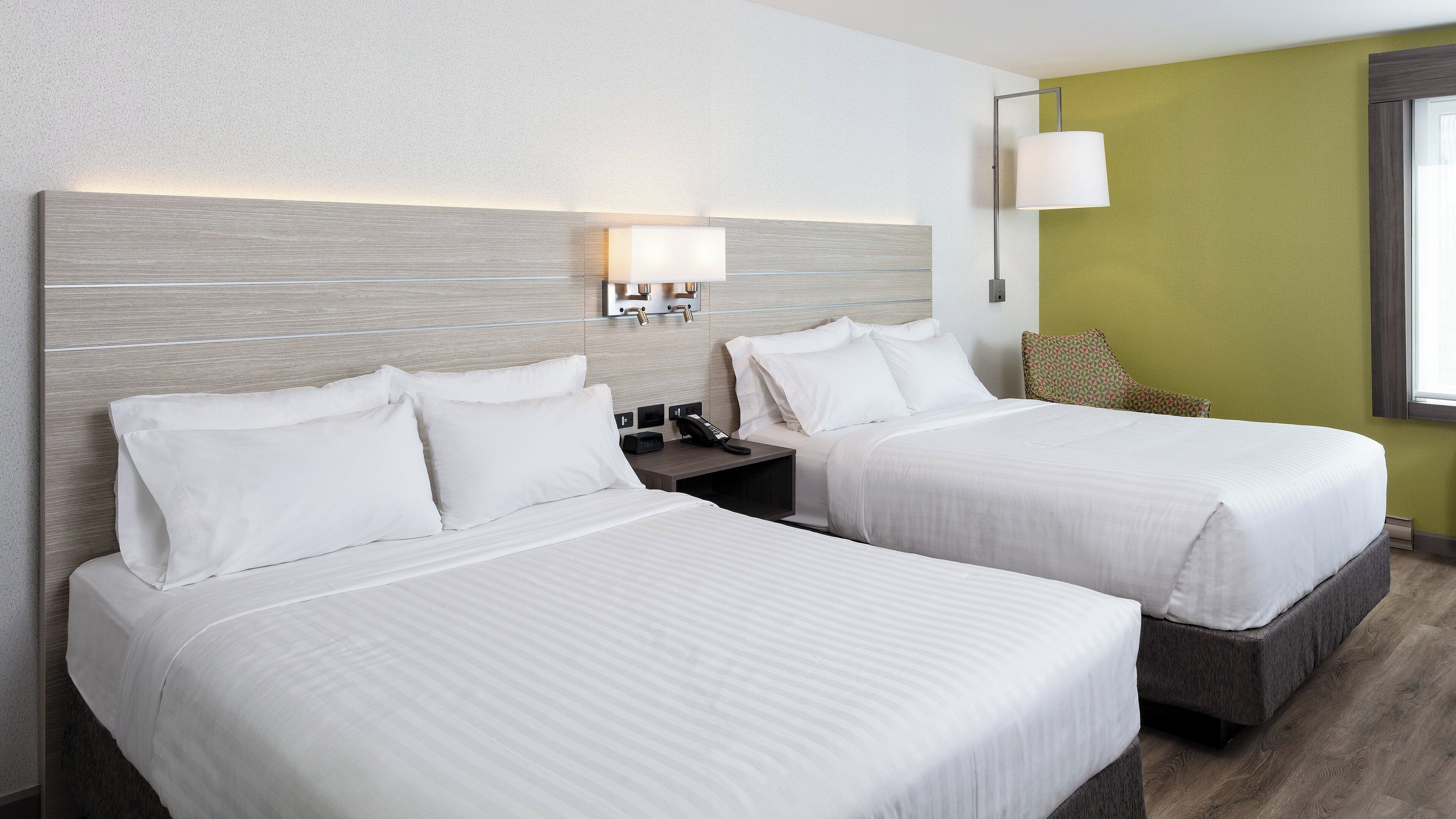 Une chambre d’hôtel avec deux lits, une table de chevet, une lampe et un téléphone fixé au mur.