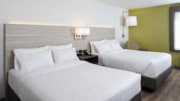 Une chambre d’hôtel avec deux lits, une table de chevet, une lampe et un téléphone fixé au mur.