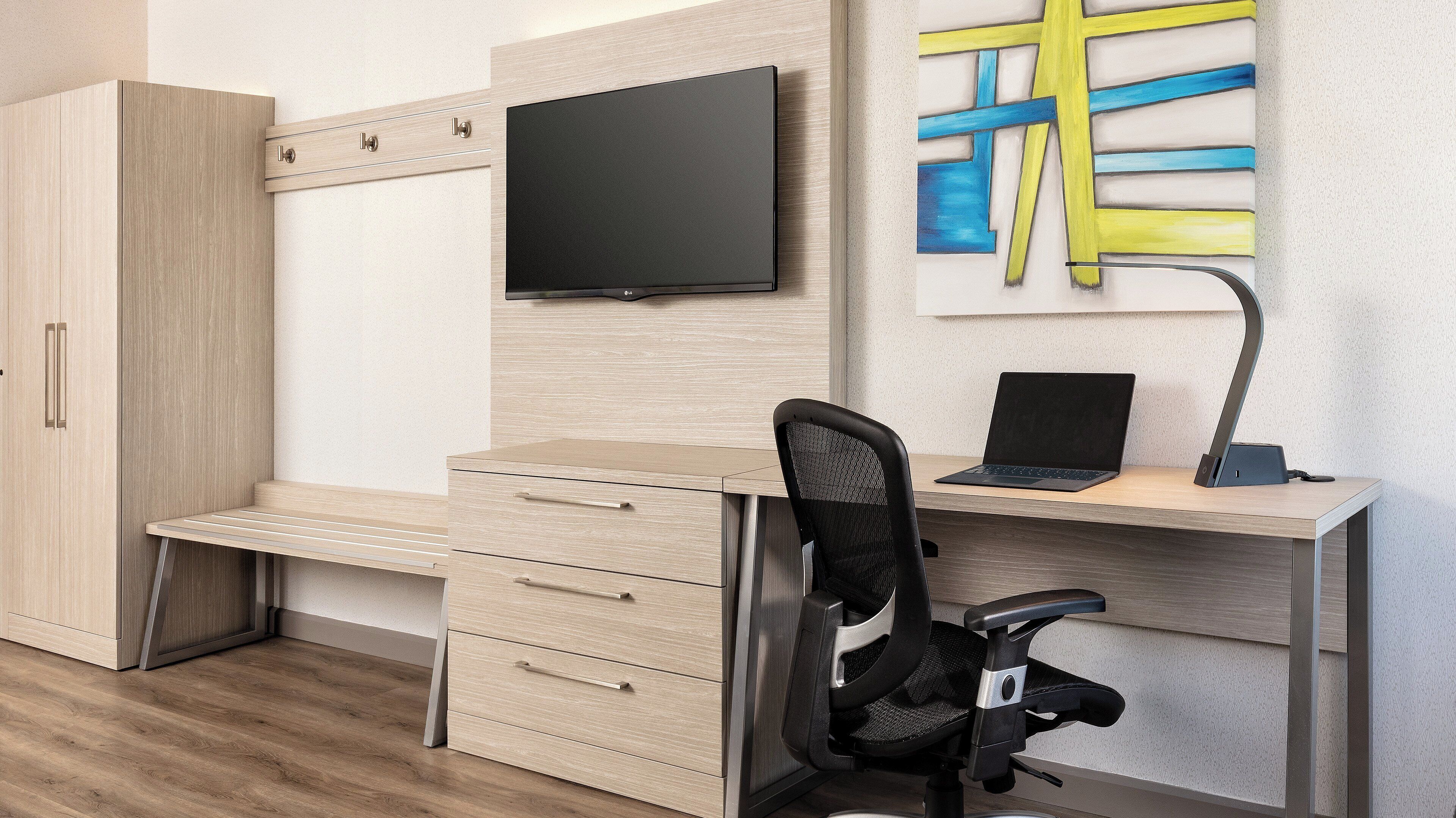 A modern office space with a desk, chair, and a mounted television.