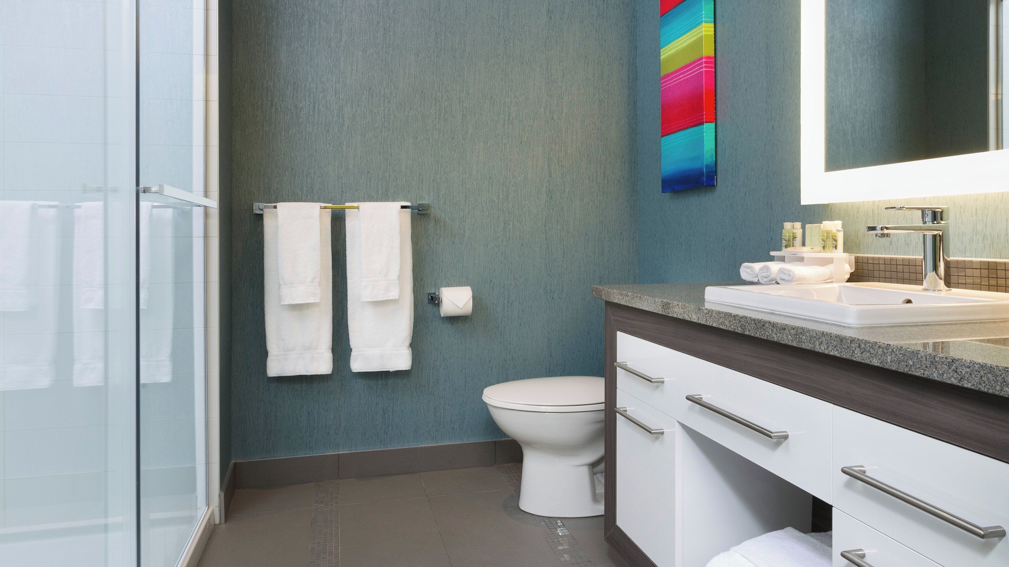 A modern bathroom with a shower, toilet, and vanity.