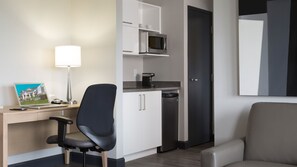 A hotel room with a desk, chair, microwave, coffee maker, and a door. - Holiday Inn Express Quebec City - Sainte Foy by IHG (Québec City)