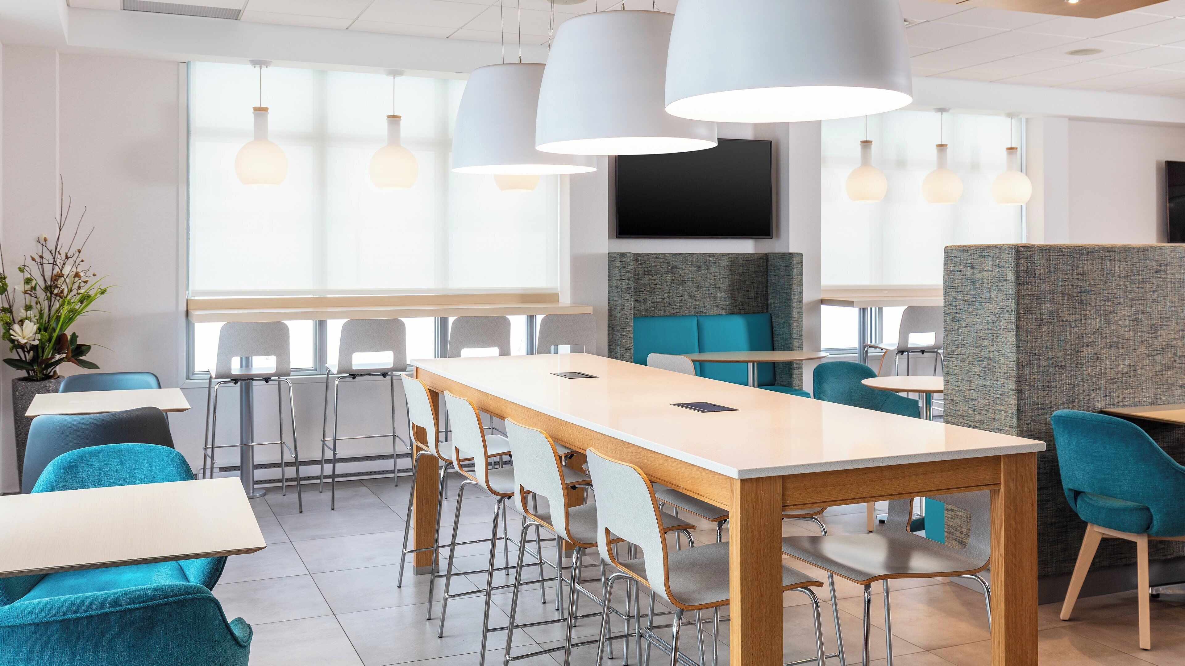Un comedor moderno con mesas altas, sillas e iluminación colgante.
