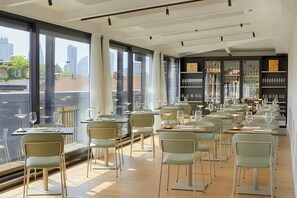 A restaurant with tables set for dining, large windows, and a view of the cityscape. - UNA Hotels Galles Milano (Milan)