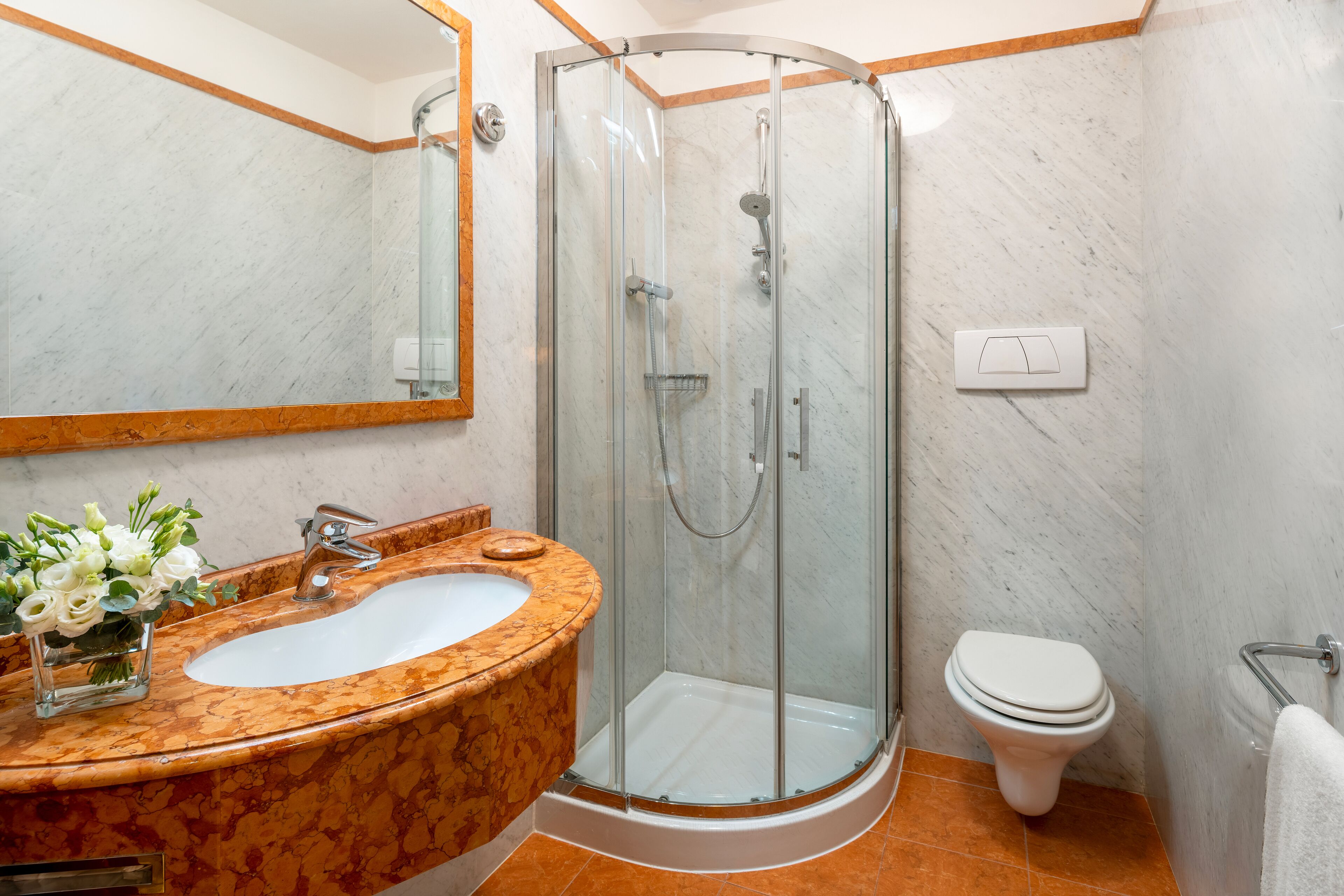 Une salle de bain avec un lavabo en marbre, une douche à parois de verre et des toilettes.