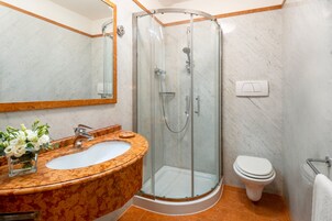 Une salle de bain avec un lavabo en marbre, une douche à parois de verre et des toilettes.