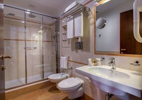 Un bagno moderno con doccia vetrata, lavandino con specchio e due servizi igienici.