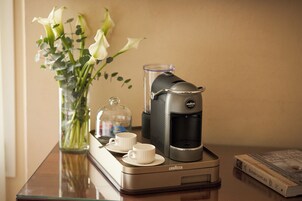 Una caffettiera su un tavolo con un vaso di fiori e due tazze.