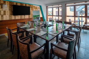 Una sala conferenze con un lungo tavolo, sedie e una televisione a schermo piatto appesa al muro.