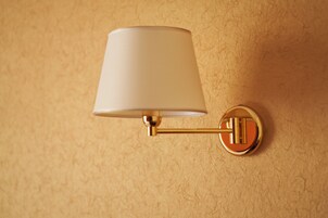 Una lampada a parete con paralume bianco e base dorata.