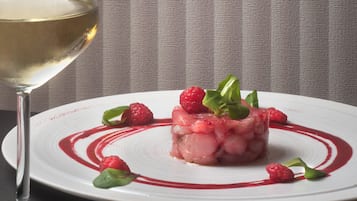 Un plato de comida con una copa de vino blanco, un tenedor y una servilleta sobre una mesa.