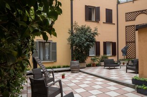 Un cortile con posti a sedere all'aperto, piante in vaso e un grande albero.