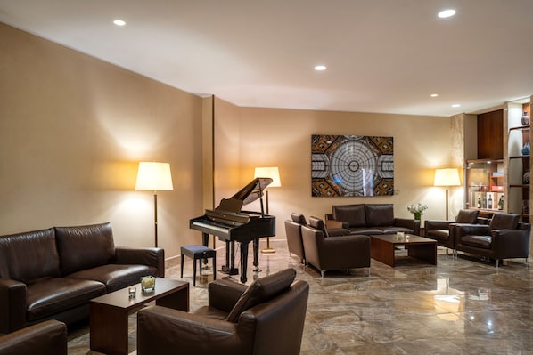 Relax in style with a grand piano, leather sofas, and a large abstract artwork in this elegant living room.