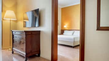 Una habitación de hotel con un aparador de madera, una cama y un televisor montado en la pared.