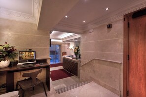 A hotel lobby with a reception desk, a television, a seating area, and a staircase. - Galileo (Rome)
