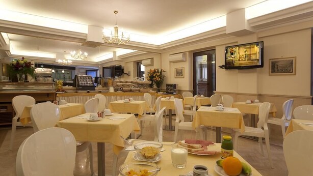 Zona de menjador amb taules preparades per esmorzar, incloent plats de fruita, menjar i begudes.