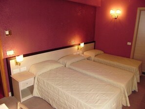 Une chambre avec deux lits, une table de chevet avec une lampe et un bureau avec une chaise.